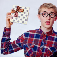 teen boy with glasses holding up gift