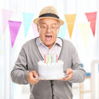 older man holding birthday cake